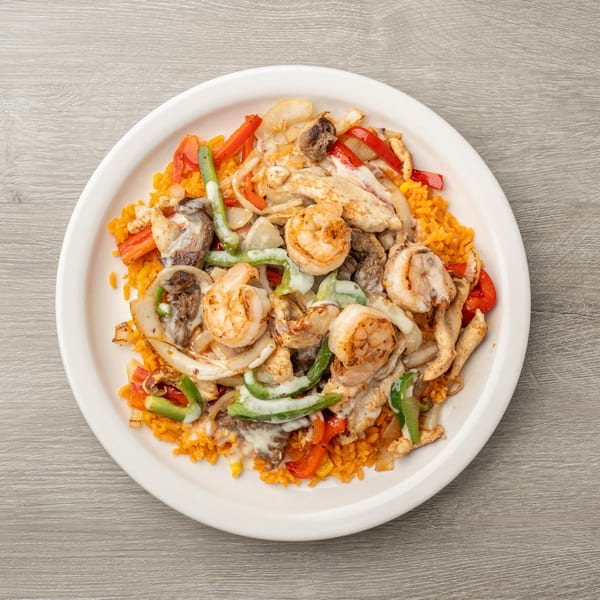 A white plate of orange rice topped with shrimp, chicken, steak, and vegetables in a creamy sauce.