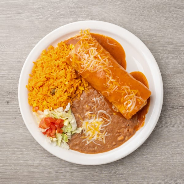 A burrito covered in red sauce and cheese, with rice, refried beans, and salad on a white plate.