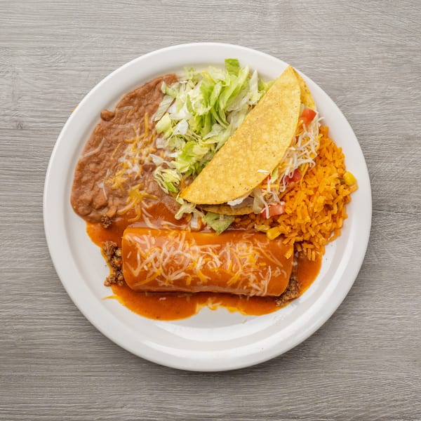 A white plate holds a burrito, taco, refried beans, rice, and shredded lettuce.
