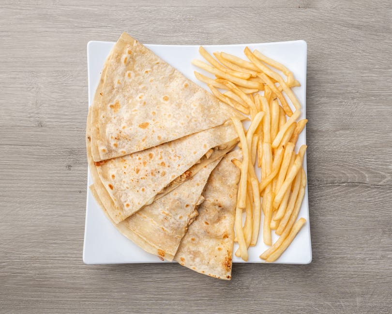 Chicken quesadillas and french fries on a white rectangular plate, on a light wooden table.