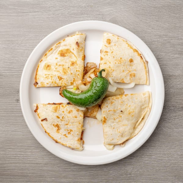 Four quesadilla wedges with melted cheese, grilled onions, and a green chili pepper on a white plate.